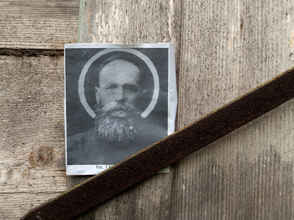 Kliknij aby powiększyć Fotografia Eliasza Klimowicza wetknięta za okiennicę domu.